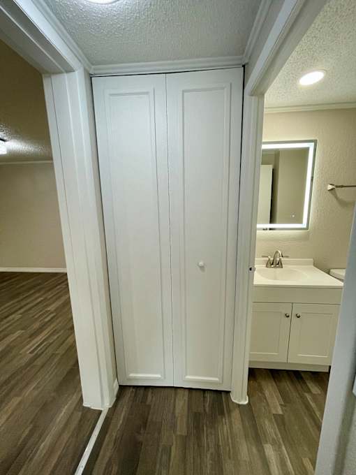 A white bathroom with a sink and a wooden floor.
