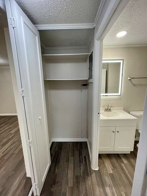 A white bathroom with a wooden floor and a white sink.