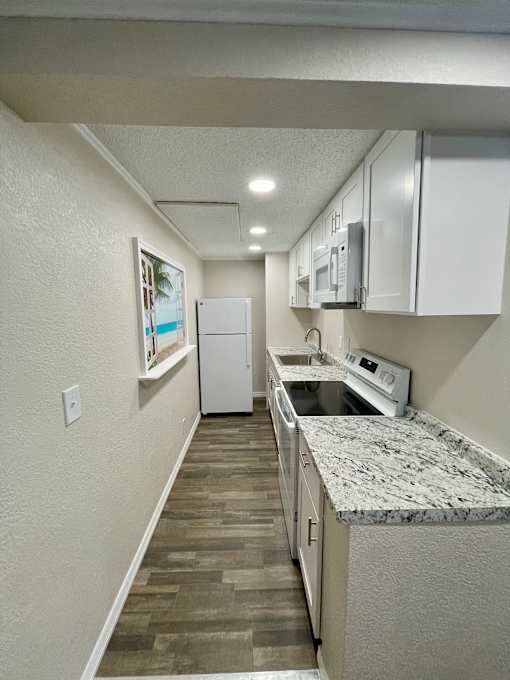 A kitchen with a white refrigerator, microwave, and oven.