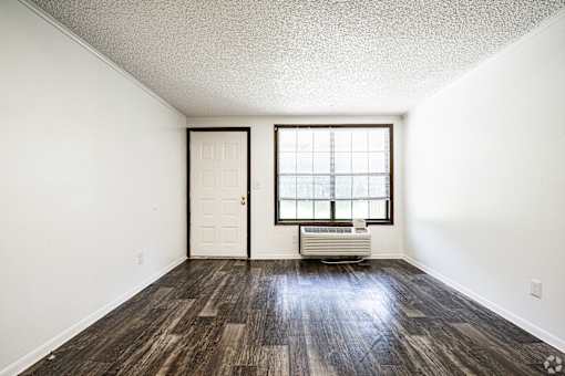 A room with a wooden floor and a window with blinds.