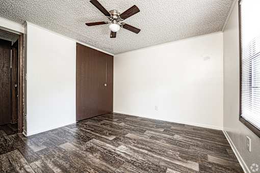 A room with a ceiling fan and wood flooring.