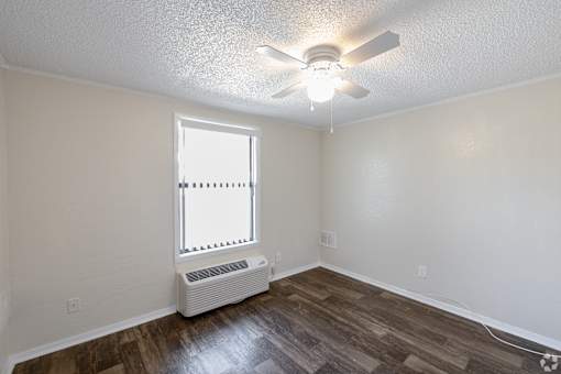 A room with a ceiling fan and a window with blinds.
