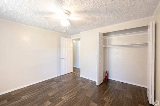 A room with a ceiling fan and wooden flooring.