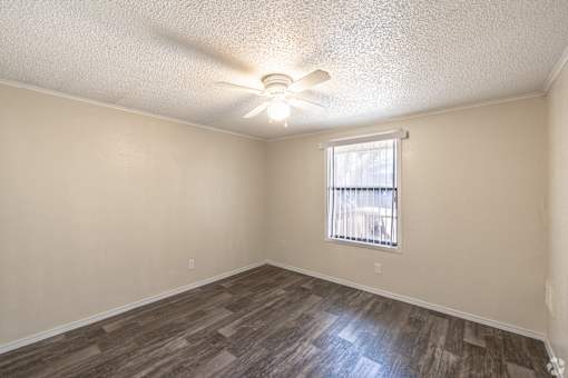 A room with a ceiling fan and a window with blinds.