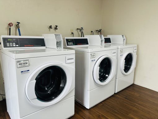 a group of washing machines and dryers in a laundry room