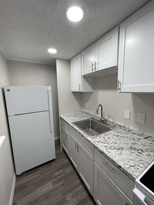 A kitchen with white cabinets and a marble backsplash.