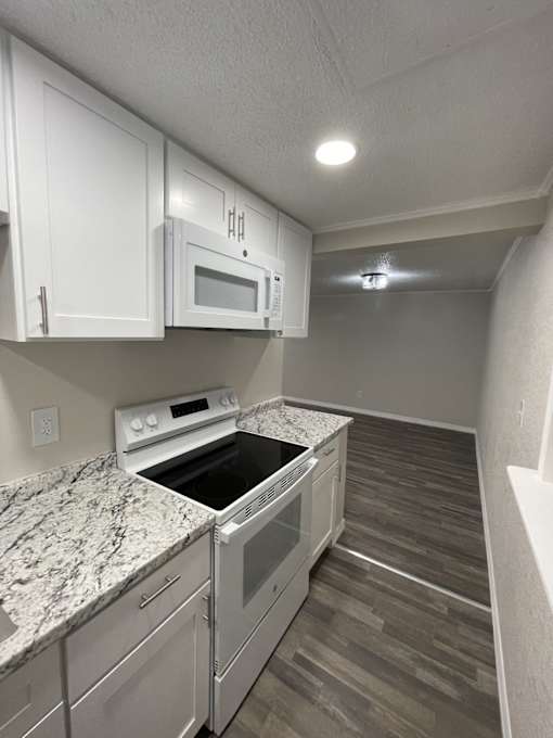 A kitchen with a microwave, oven, and stove top.