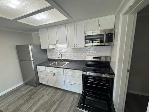 A kitchen with white cabinets and a black stove top oven.