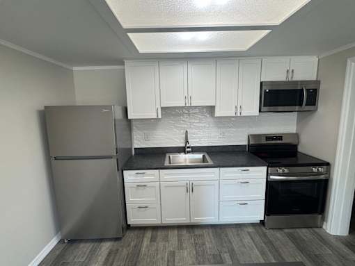 A kitchen with a refrigerator, sink, and oven.