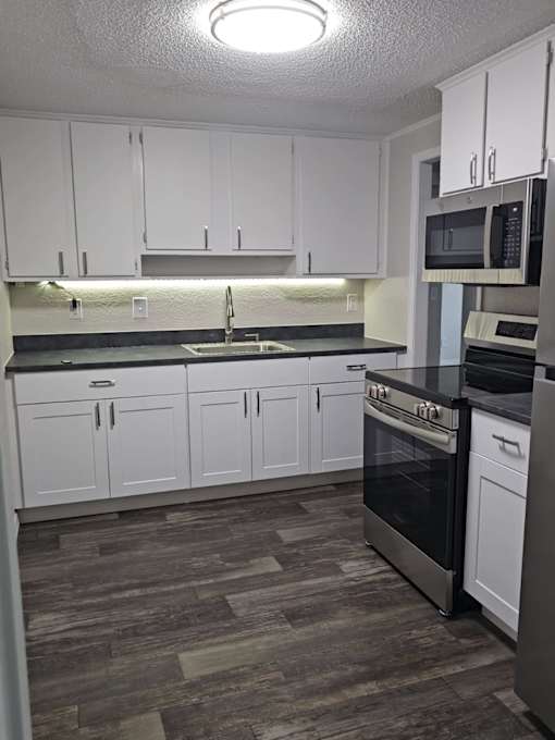 A kitchen with white cabinets and a black stove top oven.