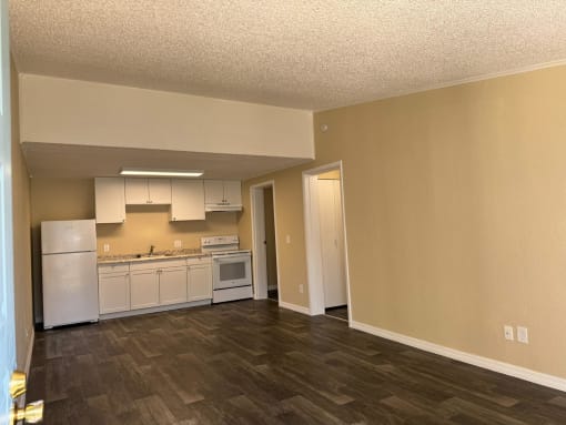 an empty kitchen with white appliances and a hard wood floor