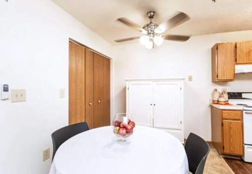 A dining room with a white table and a bowl of fruit on it.