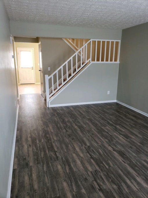an empty living room with wood floors and a staircase