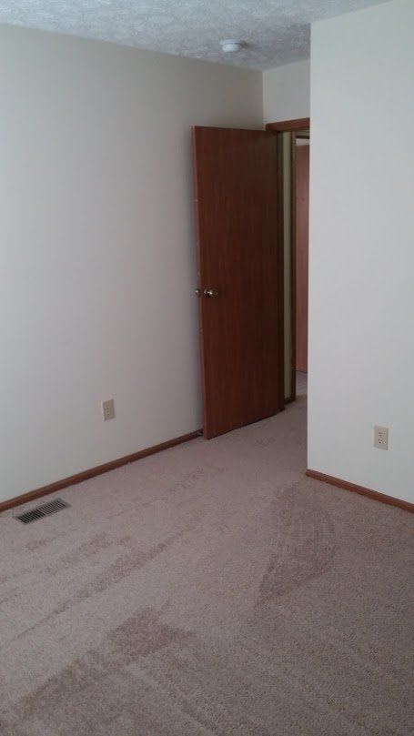 an empty room with a door and a carpeted floor
