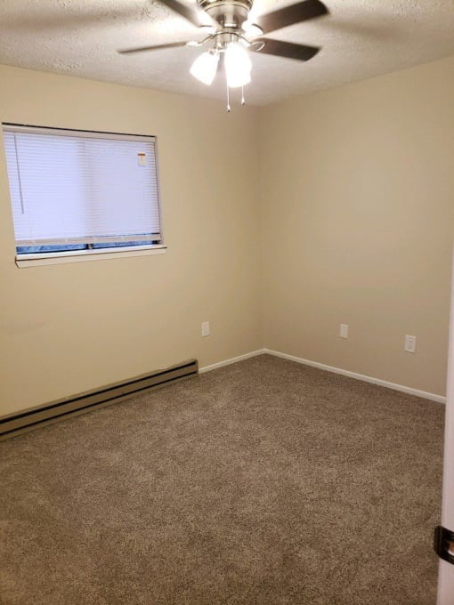 an empty room with a window and a ceiling fan