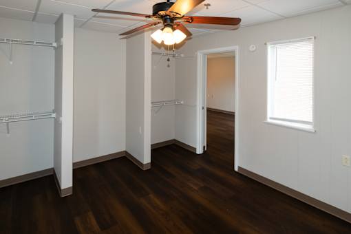 A room with a ceiling fan and wooden floors.