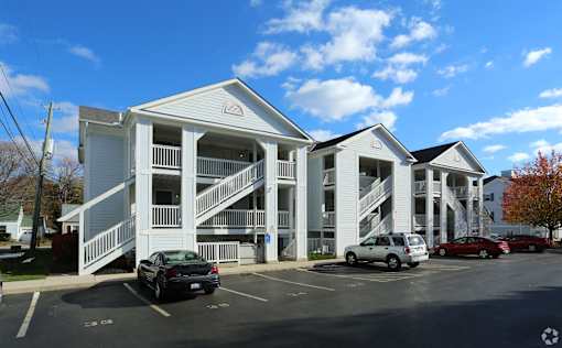 A parking lot with cars and a building with a staircase.