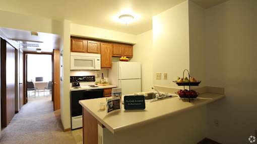 A kitchen with a refrigerator, microwave, oven, and sink.