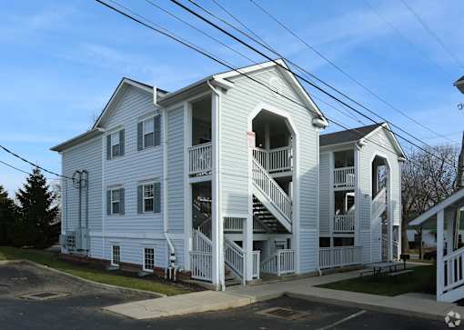 A white two-story building with a balcony on the second floor.