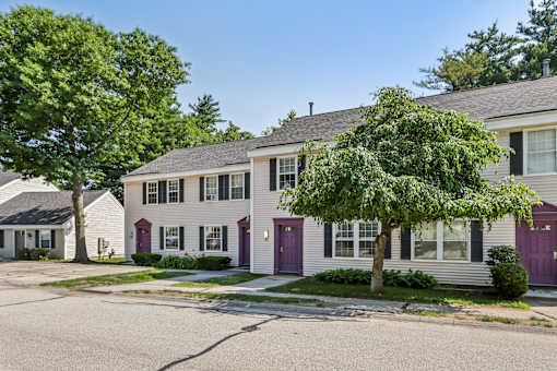 A row of houses with trees in front of them.