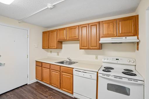 A kitchen with white appliances and wooden cabinets.