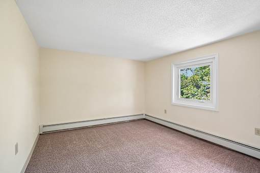 A room with a window and carpeted floor.