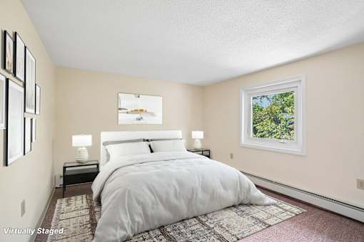 A bedroom with a large bed and a window showing trees outside.
