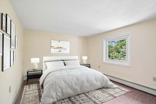 A bedroom with a large bed and a window showing greenery outside.