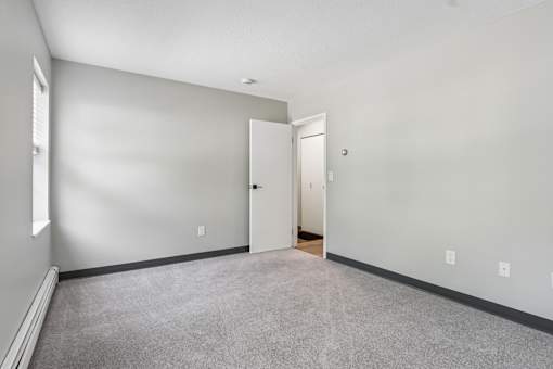 A room with a carpeted floor and a door on the right side.