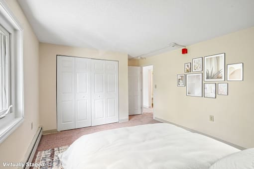 A bedroom with a white bed and a wall of pictures.