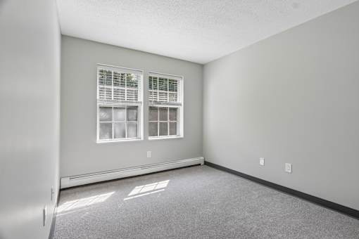 A room with a window and a carpeted floor.