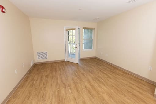 A room with wooden flooring and a door leading to another room.