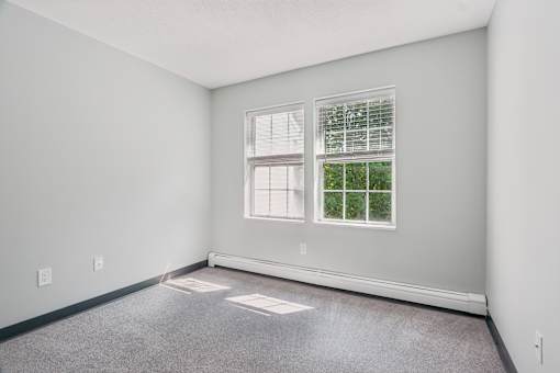 A room with a window and a carpeted floor.