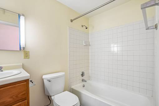 A white toilet sits next to a white bathtub in a bathroom.