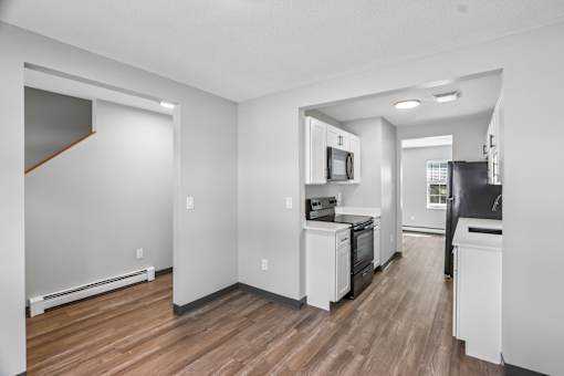 A kitchen with white appliances and wood floors.