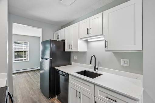 A kitchen with black and white cabinets and a black fridge.