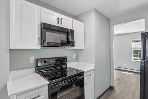 A kitchen with a stove, microwave, and cabinets.