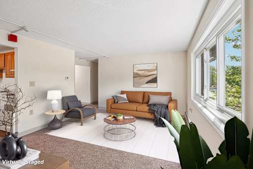 A living room with a brown couch and a painting on the wall.
