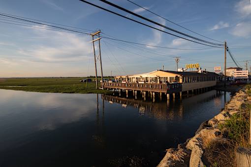 A long pier extends into a body of water with a building on it.