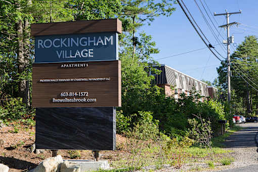 A sign for Rockingham Village Apartments sits in front of a building.