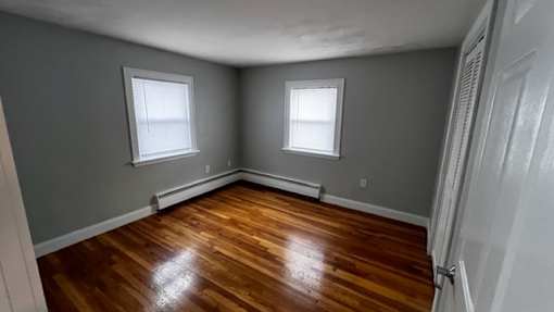 A room with wooden floors and two windows.
