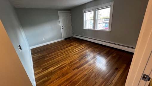 A room with wooden flooring and a window.