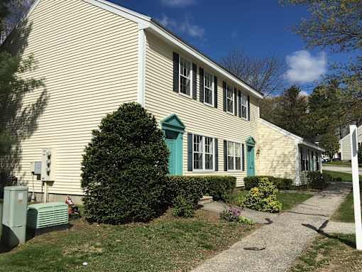 A house with a green door and a green bush in front.