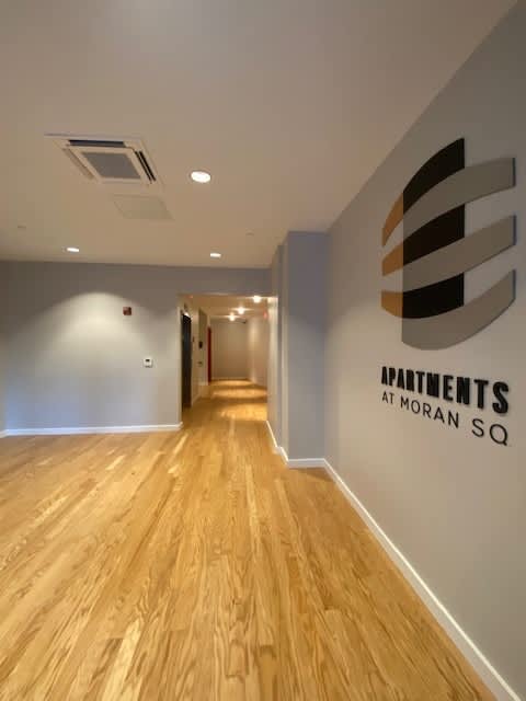 A hallway with a logo on the wall that says "Apartments at Moran Sq".