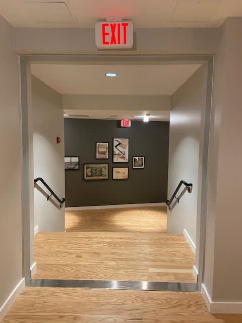 A hallway with a red exit sign above the stairs.