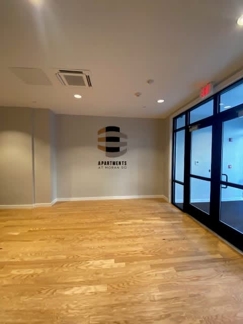 A hallway with a wooden floor and a wall with a sign that says "apartments".
