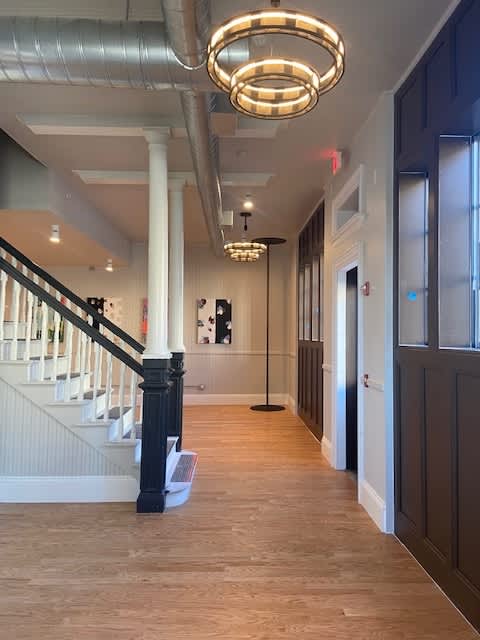 A hallway with a staircase and a chandelier.
