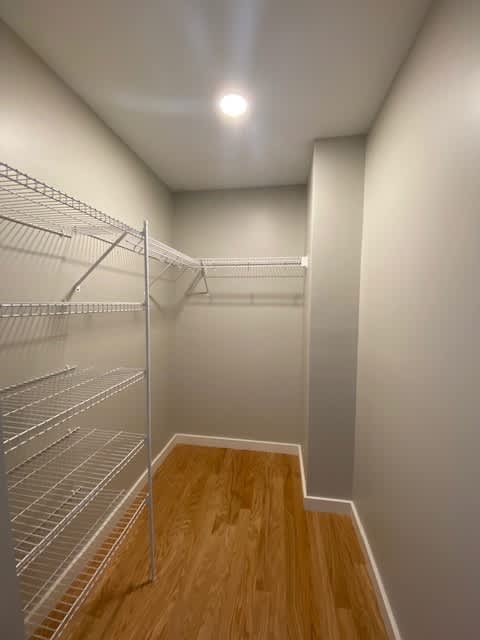 Empty walk-in closet with wooden floors and metal shelving.