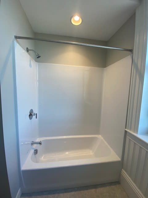 A white bathtub with a shower head and faucet.