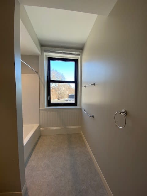 A long hallway with a window and a white door.